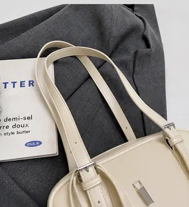Detalle de la hebilla de pasador ajustable y la cremallera plateada del bolso beige