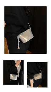 Détail du sac seau argenté miroir avec fermeture à cordon et breloque en cœur