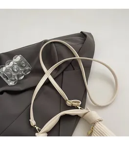 Detail of minimalist pea bag featuring golden metal buckles and stylish side knot strap