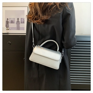 Silver PU leather flap handbag with metallic finish worn as a crossbody bag by a model