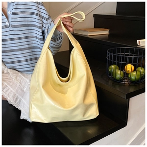 Detail of light yellow soft leather hobo tote bag held by model on black stairs