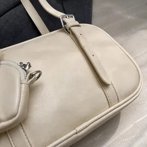 Detalle del bolso bowling de cuero crema con correa ajustable y pequeño bolso colgante