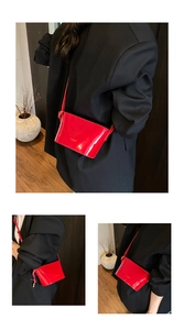 Détail du sac bandoulière en cuir verni rouge brillant avec lettrage élégant