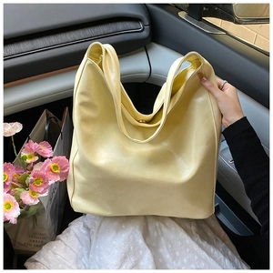 Close-up of a large pale yellow leather tote bag with magnetic clasp on a car seat