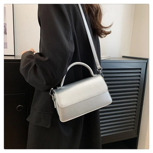 Detail view of silver metallic leather flap bag featuring sleek handle and silver hardware