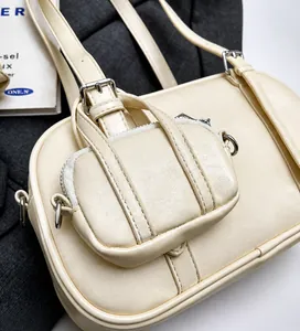 Detalle de bolso bowling de cuero blanco roto con herrajes plateados y mini monedero