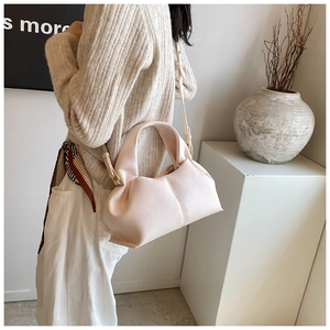 Detail of light pink pleated cloud bag with soft leather texture and slender shoulder strap