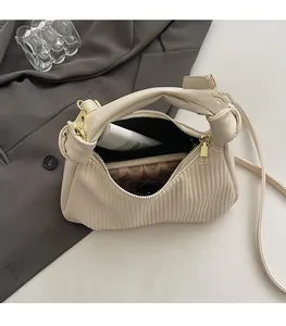 Top view of cream pleated handbag interior showing spacious black lining and gold hardware