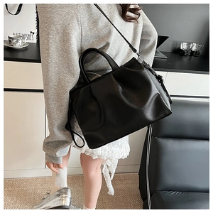 Detail der schwarzen Cloud-Tasche mit Falten-Design und Umhängeriemen in einer Lifestyle-Szene