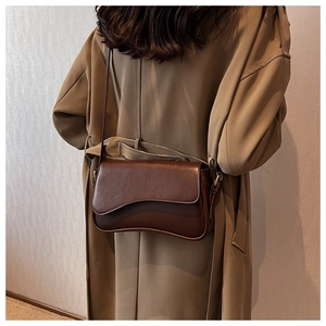 Close-up of dark brown retro crossbody bag featuring a unique wavy flap and matte leather texture