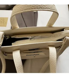 Gros plan du sac en cuir grainé avec fermeture éclair argentée et fermoir rotatif
