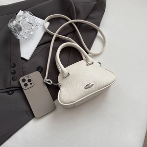 Dettaglio ravvicinato della borsa bianco crema texture litchi con ornamento in metallo argento