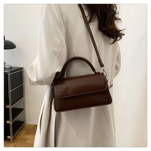 Detail of dark brown vintage leather crossbody bag worn by a model in an elegant setting