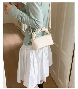 Litchi pattern cream crossbody bag shown on model with unique knotted top handle design