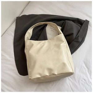 Detail of soft cream-colored leather tote bag showing wide shoulder strap on grey blazer
