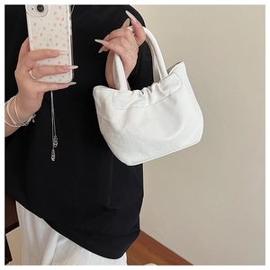 Close-up of white pleated bucket bag showing leather texture and double handles