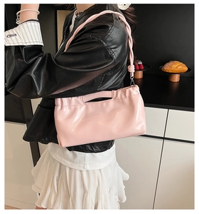 On-body view of pink glossy pleated hobo bag with unique knotted strap detail