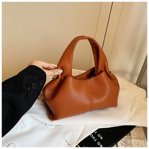 Détail macro du sac nuage en cuir grainé caramel avec boucle métallique latérale