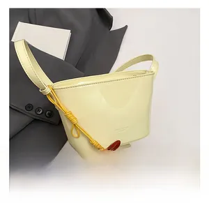 Détail du sac seau jaune clair motif lychee avec pendentif bille argentée et logo