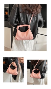 Close-up of pink pleated crescent bag showing knot handle and adjustable crossbody strap