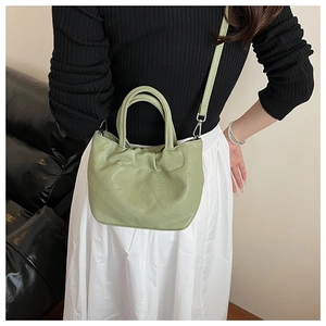 Detail of light green ruched cloud bag with silver hardware on a crossbody strap