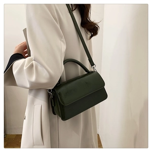 Detail of dark green glossy patent leather mini bag with silver metal buckles and top handle