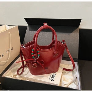 Détail d'un sac seau rouge foncé avec charms et finitions argentées en coffret cadeau