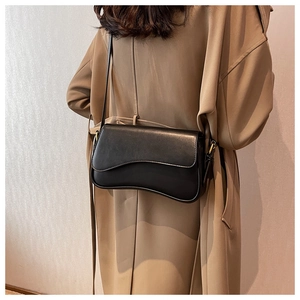 Detail view of the black leather crossbody bag featuring a unique wave-shaped bottom edge