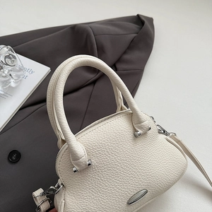 Dettaglio borsa a mano crema a grana con hardware argento su abbigliamento formale