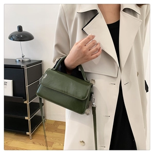 Model showcasing dark green oil-wax leather handbag with silver hardware and shoulder strap