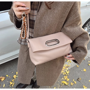 Detail of pleated accordion texture and silver metal hardware on a beige crossbody bag