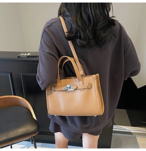 Sac fourre-tout en cuir marron grainé avec fermoir rotatif argenté porté à l'épaule