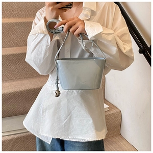 Détail du sac seau bleu clair à motif litchi avec breloque argentée et sangle