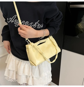 Detailed view of cream PU leather drawstring bag with glossy finish and thin shoulder strap