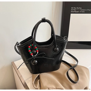 Détail du sac seau noir brillant avec breloques en perles et logo embossé
