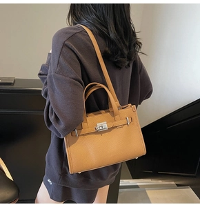 Détail de la texture cuir grainé marron chameau et boucle argentée d'un sac à main