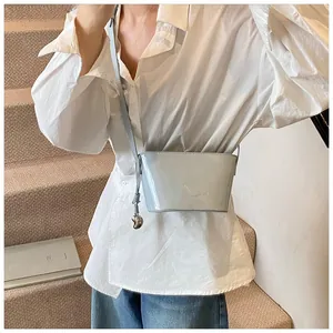 Détail du sac bandoulière en cuir verni bleu clair avec pendentif coeur élégant
