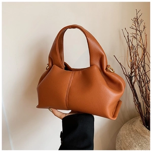 Détail du sac dumpling en cuir caramel montrant des plis souples et un grain de cuir fin