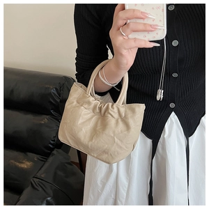 Detailed view of beige pleated bucket bag made of soft vegan leather with a ruffled design