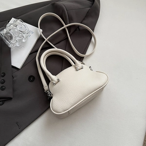 Dettaglio borsa in pelle martellata bianco crema con silhouette curva e tracolla sottile
