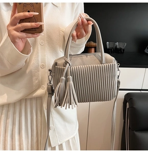 Détail du sac à main gris clair en cuir grainé avec doubles glands et fine bandoulière