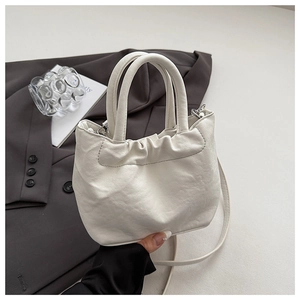 Detail of white pleated cloud bag with tubular handles and adjustable shoulder strap