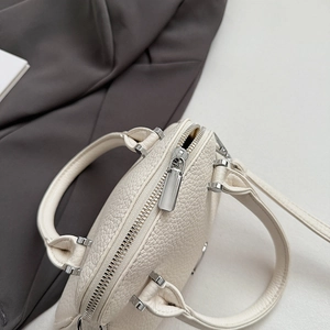 Dettaglio borsa in pelle martellata bianco crema con zip e fibbie in metallo argento