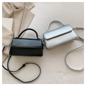 Detailed view of glossy textured leather crossbody bags in black and silver finishes