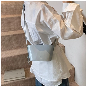 Mannequin portant un sac seau bleu clair avec pendentif sphérique sur l'escalier
