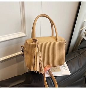 Detail of beige pleated leather handbag with long fringe tassel and lychee texture finish
