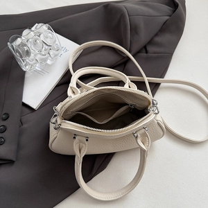 Dettaglio interno della borsa in pelle beige con manici rotondi e finiture metalliche