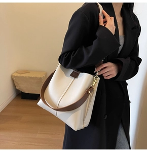 Close-up of beige leather tote bag with brown straps and vertical stitching detail