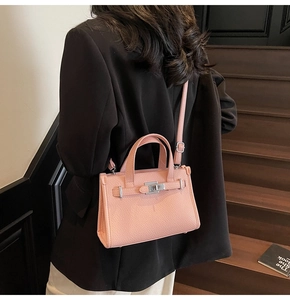 Sac bandoulière en cuir grainé rose avec fermoir argenté sur fond de costume noir