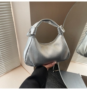 Detail of silver pleated crescent bag with knotted handle and metallic texture